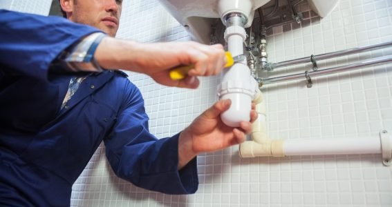 Frowning plumber repairing sink in public bathroom